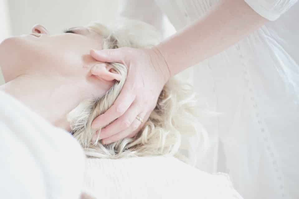 אישה עם שיער בלונדיני עוברת עיסוי ותרגילים לקרקפת