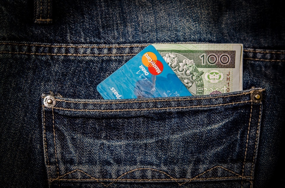 כרטיס אשראי וכסף מזומן בתוך כיס אחורי של ג'ינס