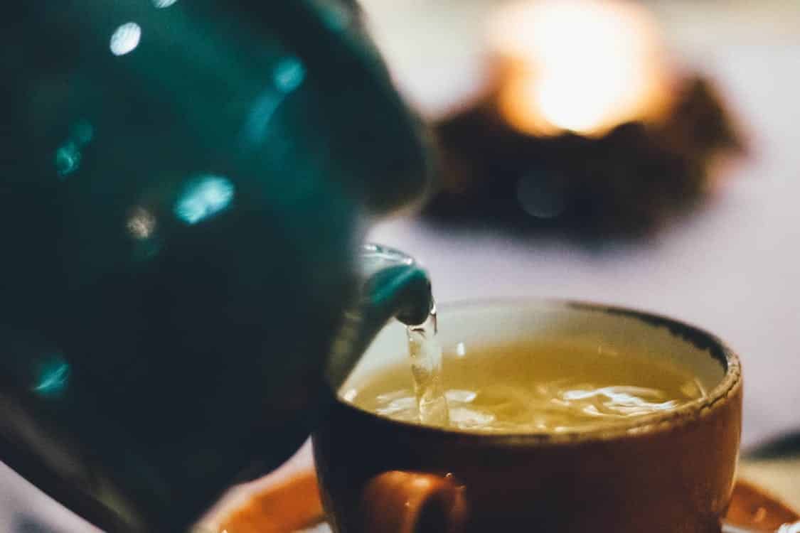 קומקום מוזג תה ירוק לתוך כוס