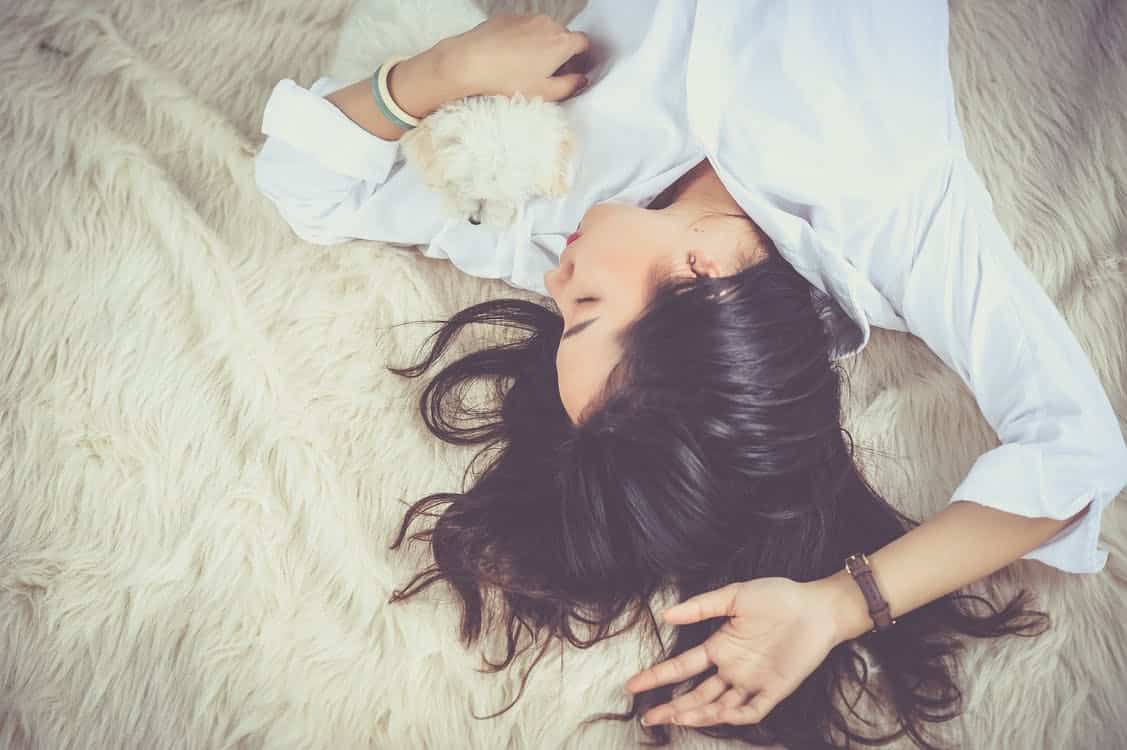 אישה שוכבת על המיטה עם שיער פזור ועיניים עצומות