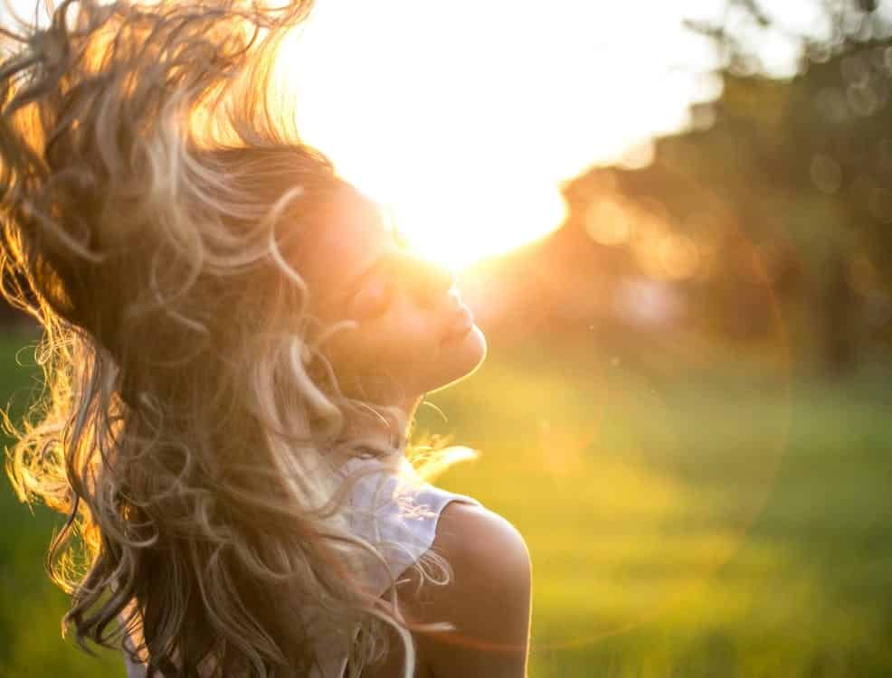 אישה בלונדינית מנופפת בשיער שלה אל מול השמש